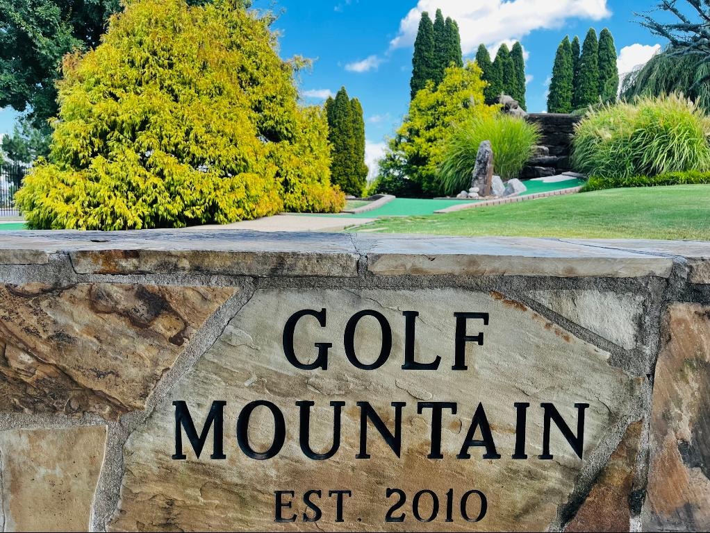 Golf Mountain Est. 2010 stone sign with lush course in background